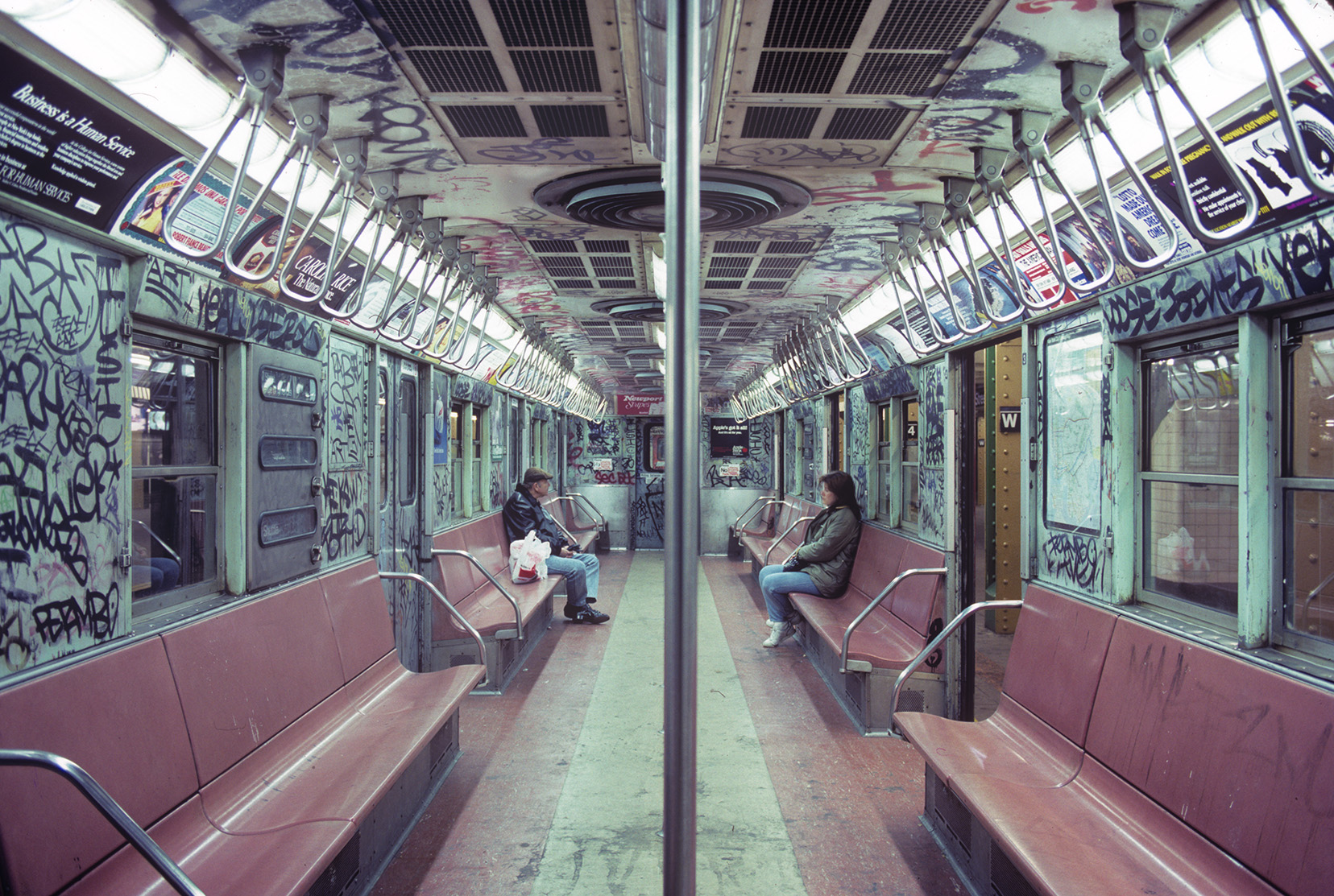 In the 1980s two subway riders on a Time Square shuttle in a car covered in graffiti in New York City